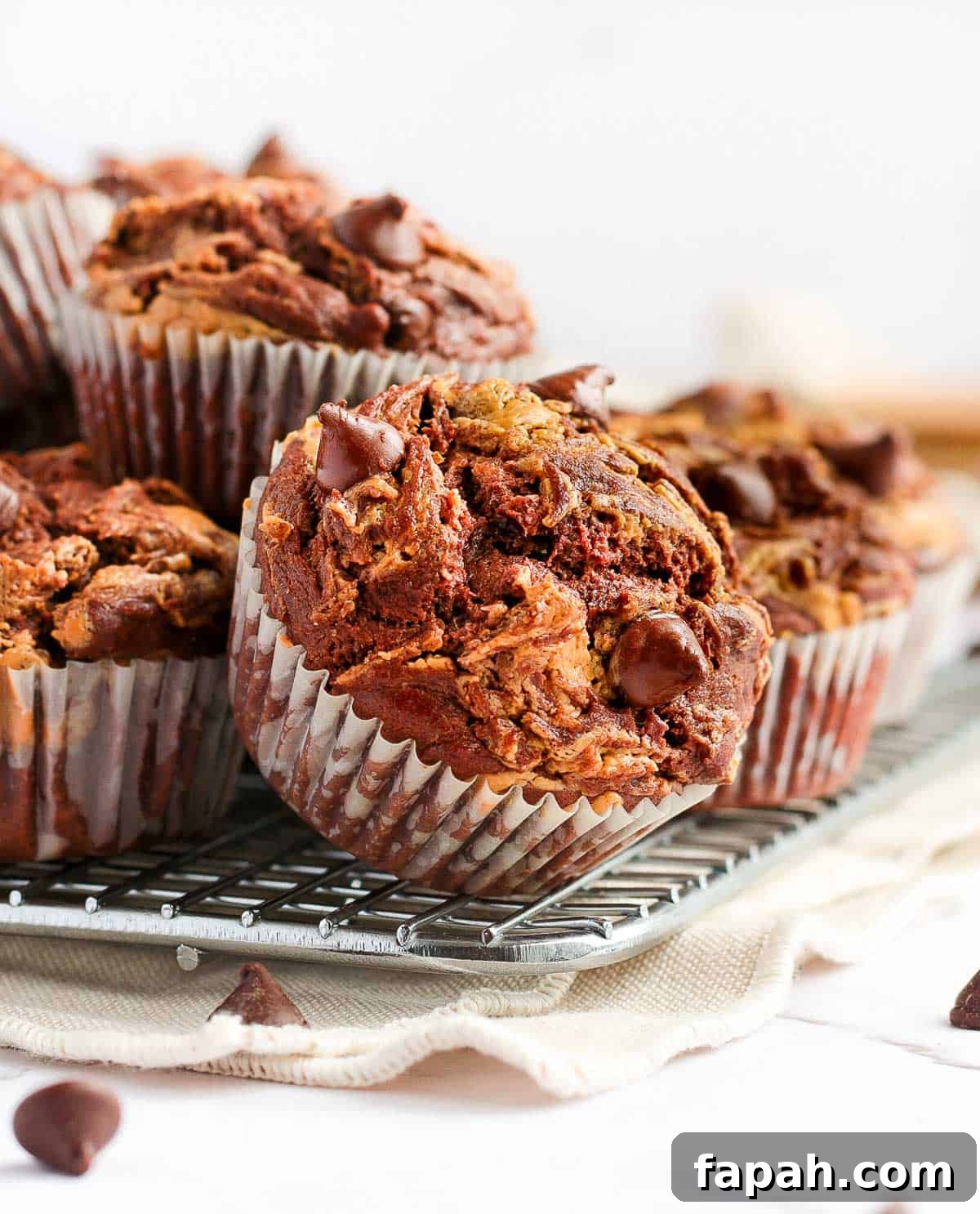 Stack of muffins over a cooling rack and a beige napkin.