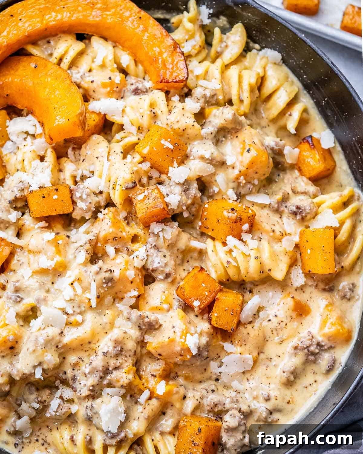 Creamy Butternut Squash Pasta close-up, showing spirals of pasta coated in sauce with tender squash and a sprinkle of cheese.