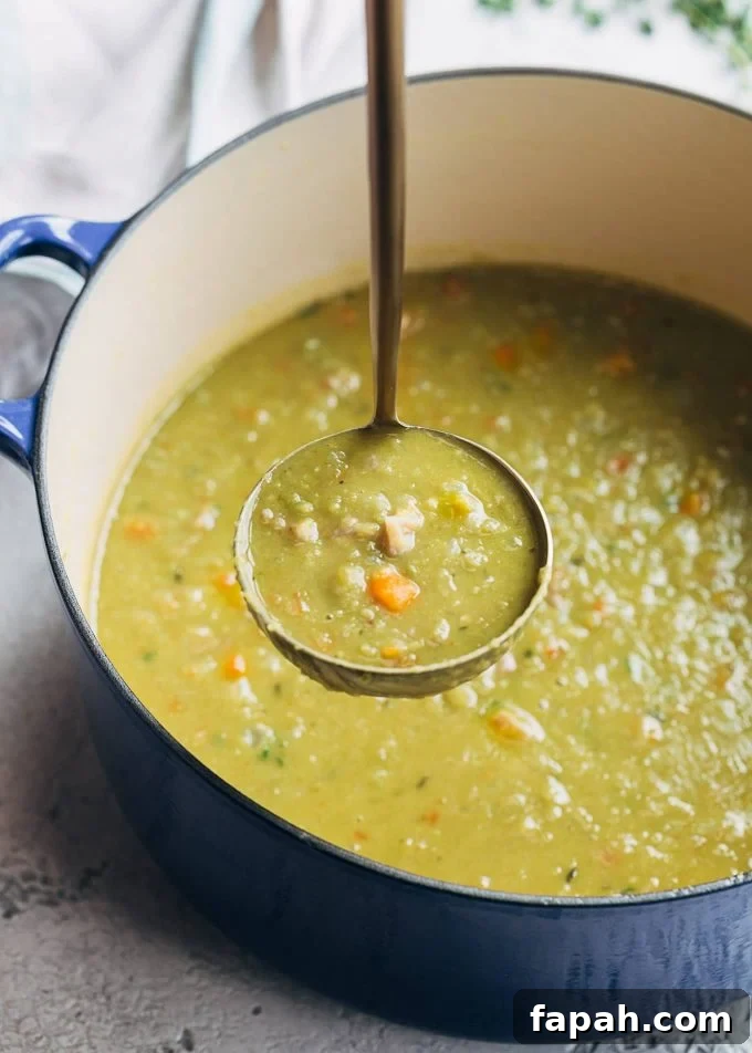 ladleful of split pea soup and ham in a blue cast iron pot