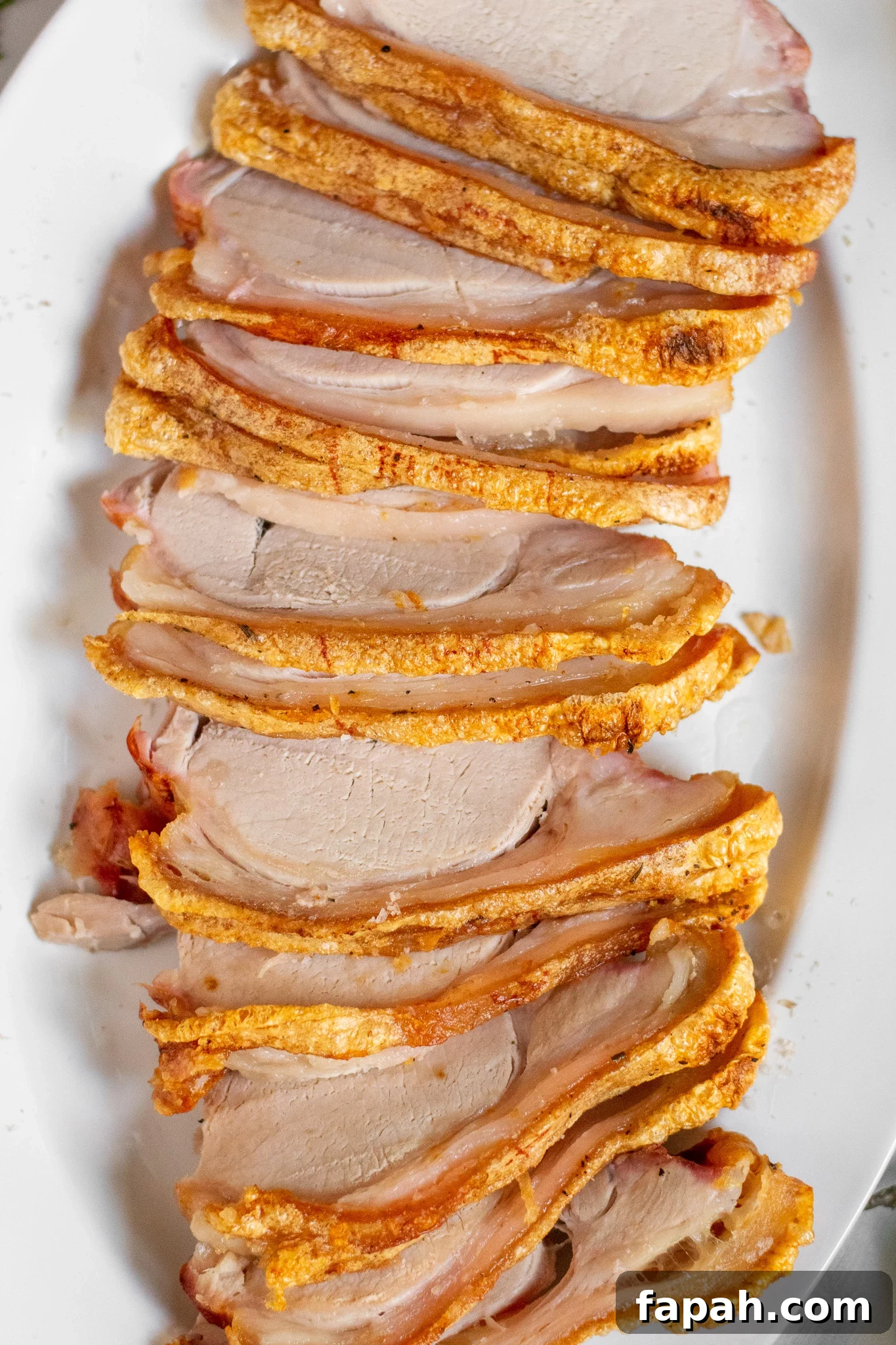 Slices of roast pork loin with crackling on a serving dish.