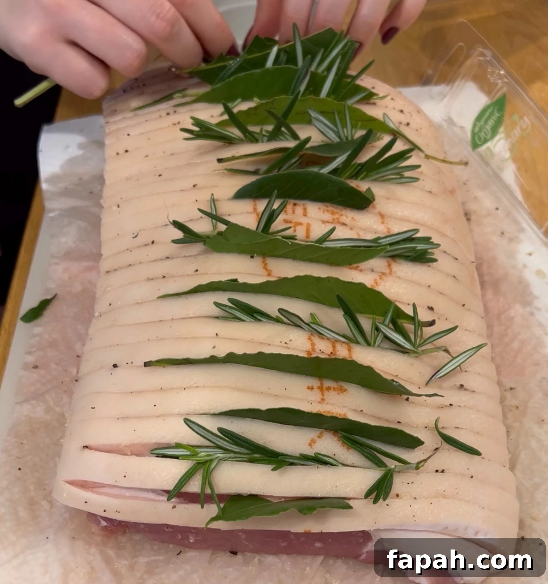 Adding bay leaves and rosemary to the top of the roast.
