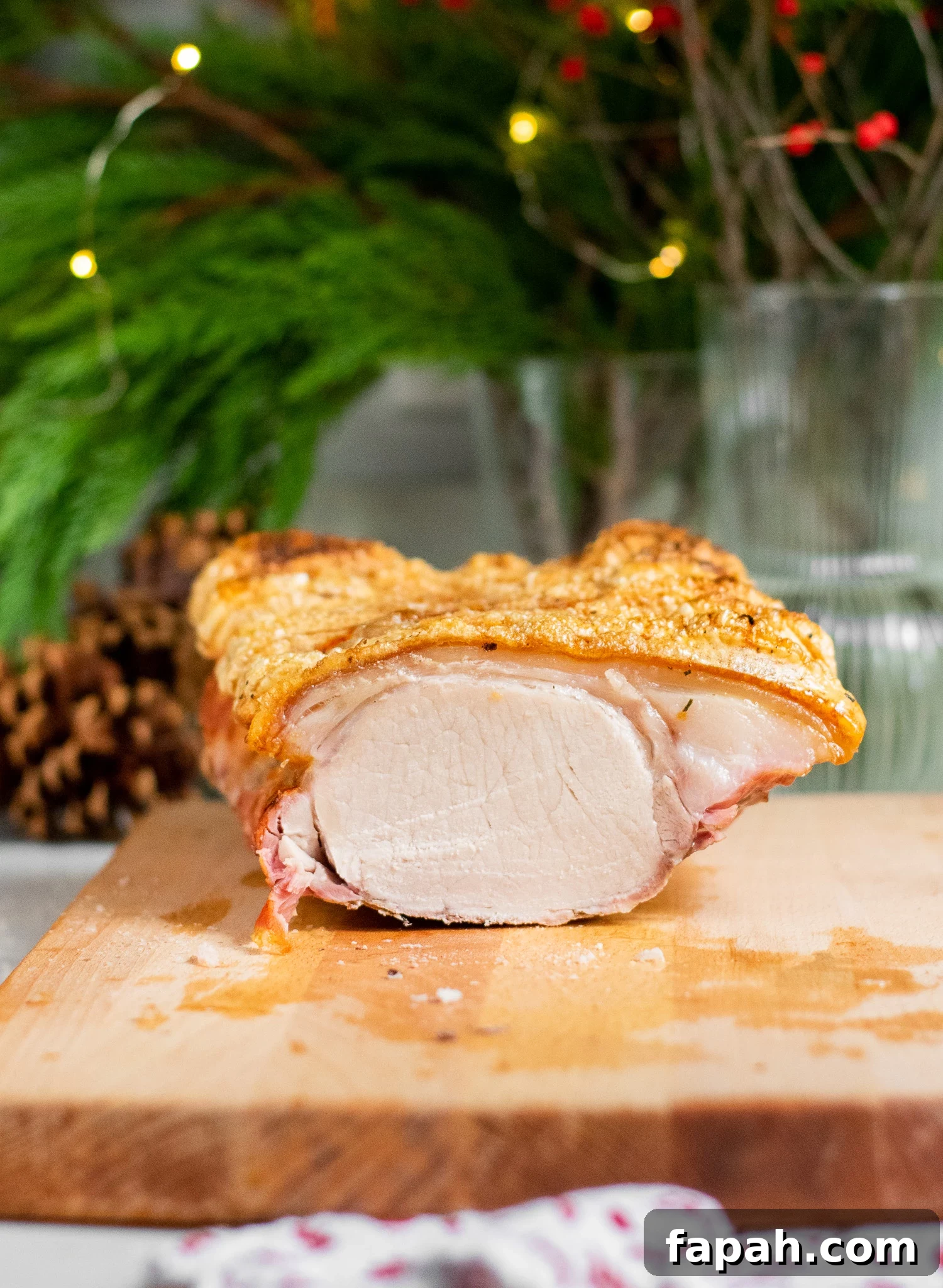 A cross section of a roast pork loin with crackling on a cutting board.