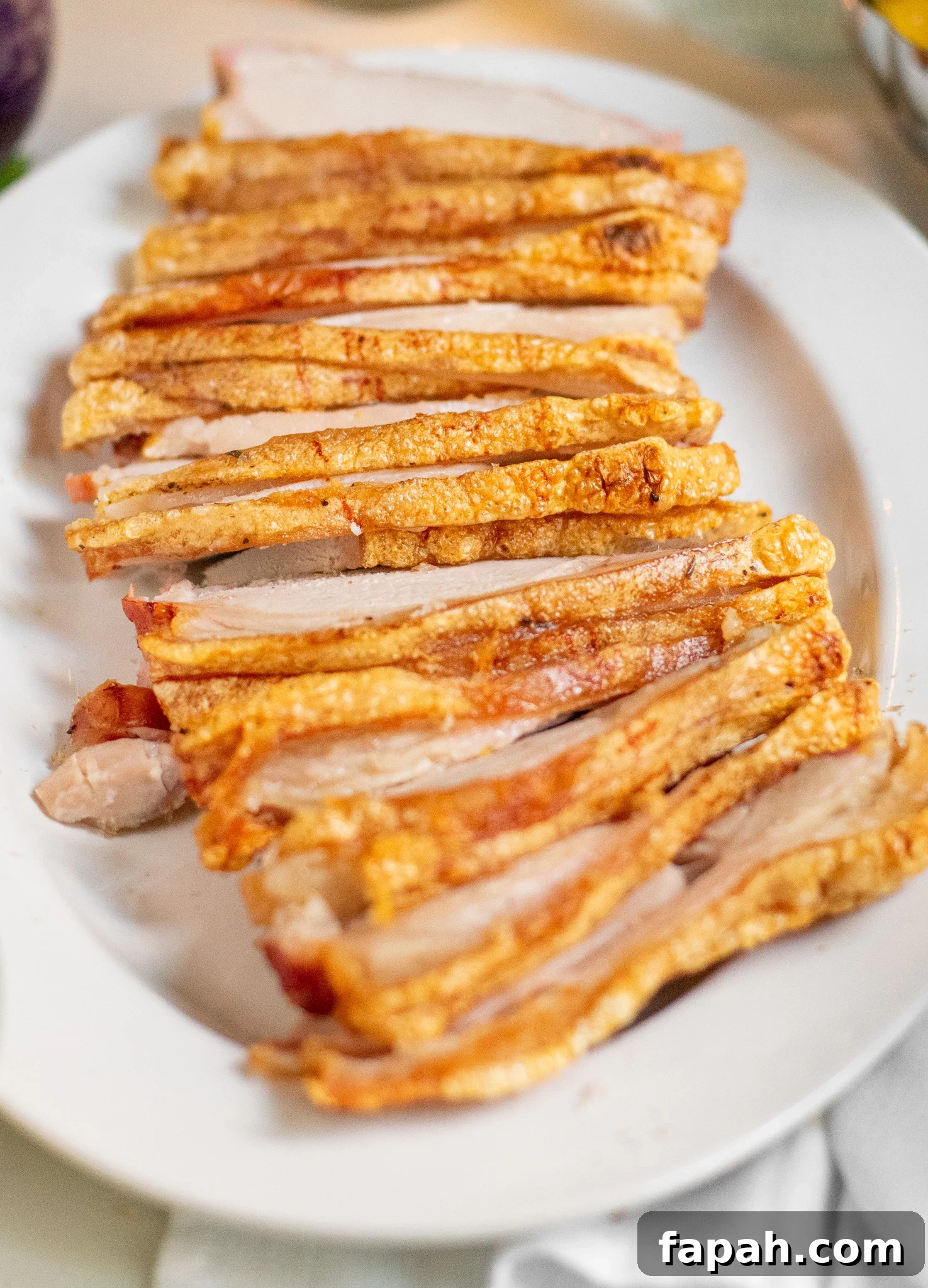 Slices of roast pork loin with crackling on a serving dish.