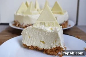 Slice of White Chocolate Toblerone Cheesecake on a white plate on a wood board.