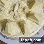 Top view of half of the White Chocolate Toblerone Cheesecake on a white plate with a wood board background.