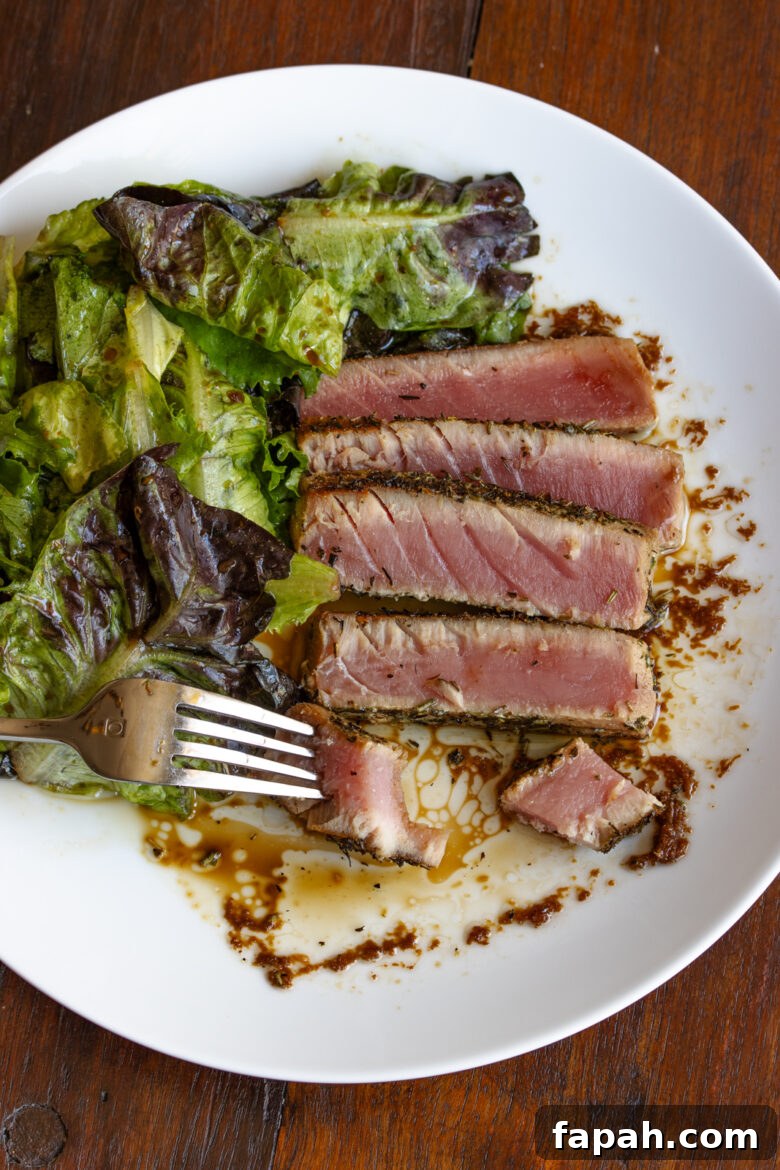 Grilled tuna on a white plate with a piece on a fork. 
