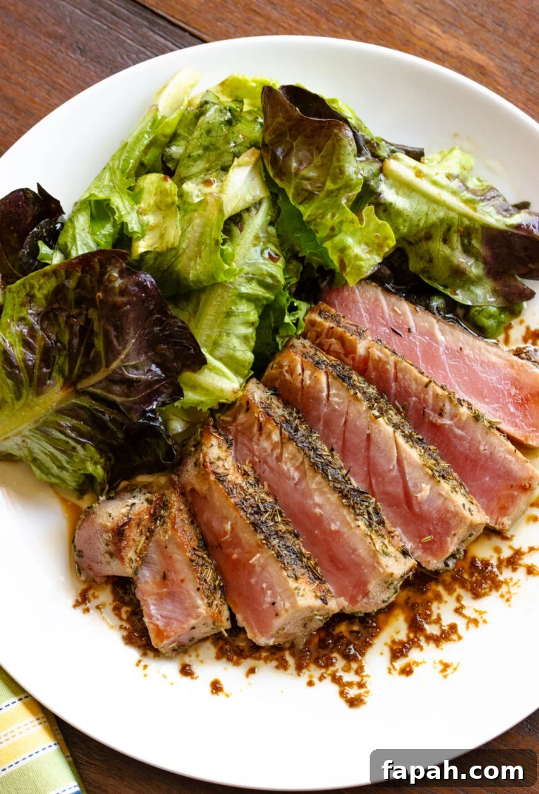 Grilled tuna with salad alongside served on a white plate. 