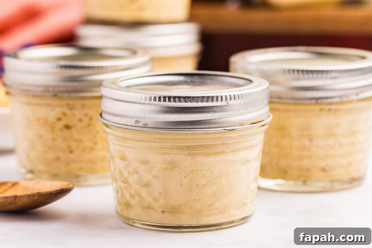 Several small glass jars filled with homemade Dijon mustard with metal lids.