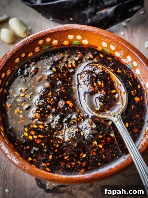 Fresh Cherry Tomato Pico de Gallo Salsa Recipe 11 Salsa macha in a terracotta bowl with a spoon on a wooden board.