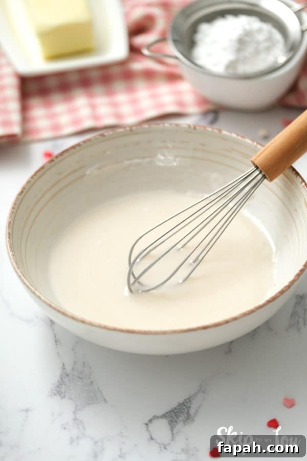 White ceramic mixing bowl with whisk and confectioner's sugar icing inside, by Skip to my Lou.