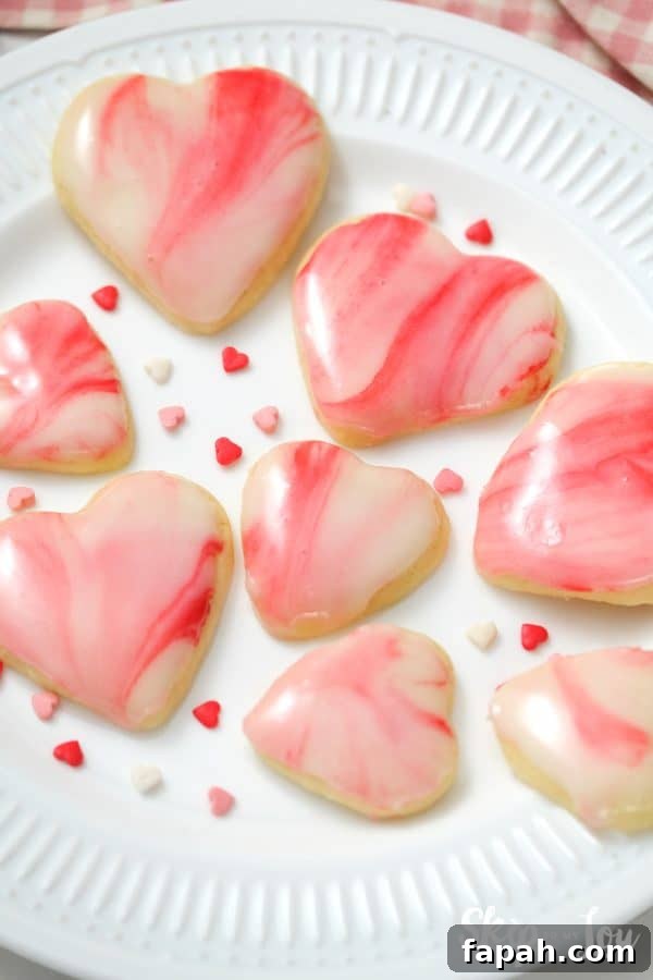 Heart shaped sugar cookie topped with a white, pink and red marbled icing, by Skip to my Lou.