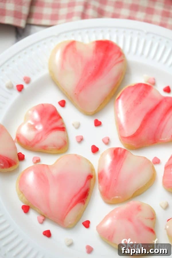 7 heart shaped sugar cookies with white, pink and red marbled icing on top, by Skip to my Lou.