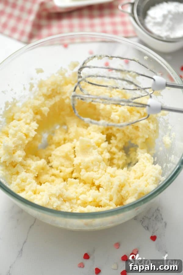 Clear glass mixing bowl with beaters and a sugar and butter mixture whipped up inside, by Skip to my Lou.