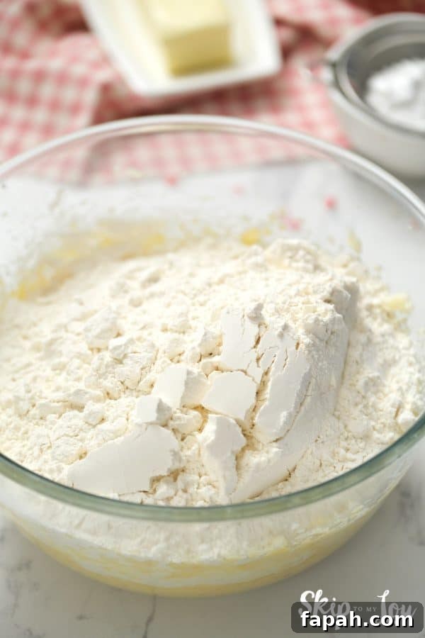 Glass mixing bowl with sugar and butter mixture on the bottom and flour on top, by Skip to my Lou.