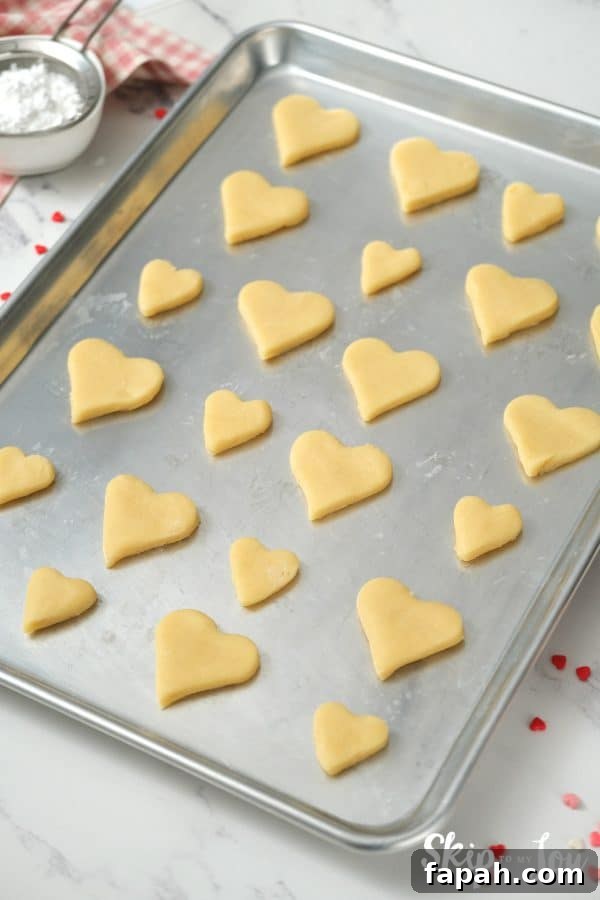 22 heart shaped cookies sitting in rows on a baking sheet before baking, by Skip to my Lou.