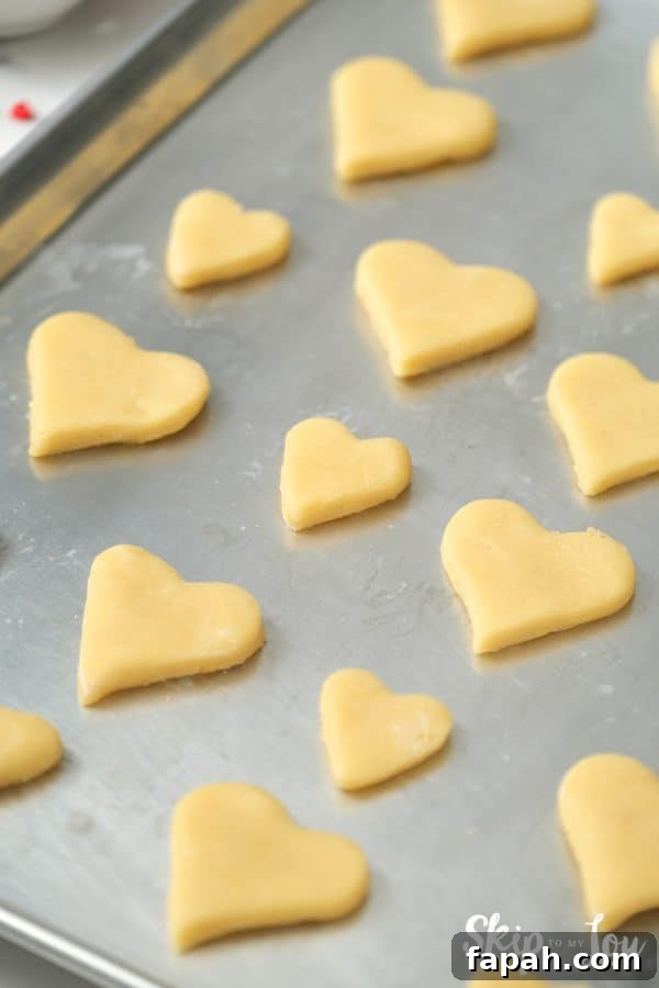 12 heart-shaped sugar cookies on a cookie sheet after baking, by Skip to my Lou.