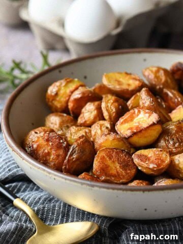 Bowl of roasted potatoes on a blue striped napkin.