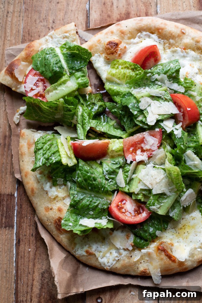 Caesar Salad Pizza Recipe: Crispy Romaine & Parmesan Pizza 4 cheese pizza with caesar salad and tomatoes on top