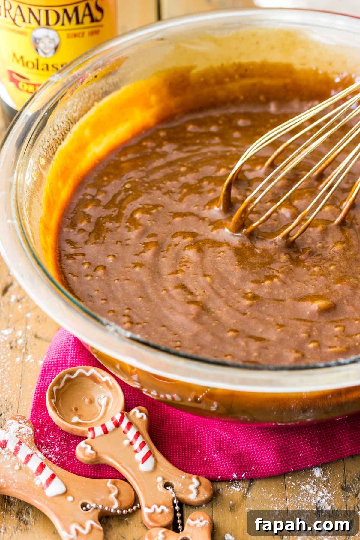 Classic Homemade Gingerbread Recipe for Soft, Spiced Cookies 4 Gingerbread batter being whisked in a glass bowl with two gingerbread cookie shaped measuring spoons inforeground