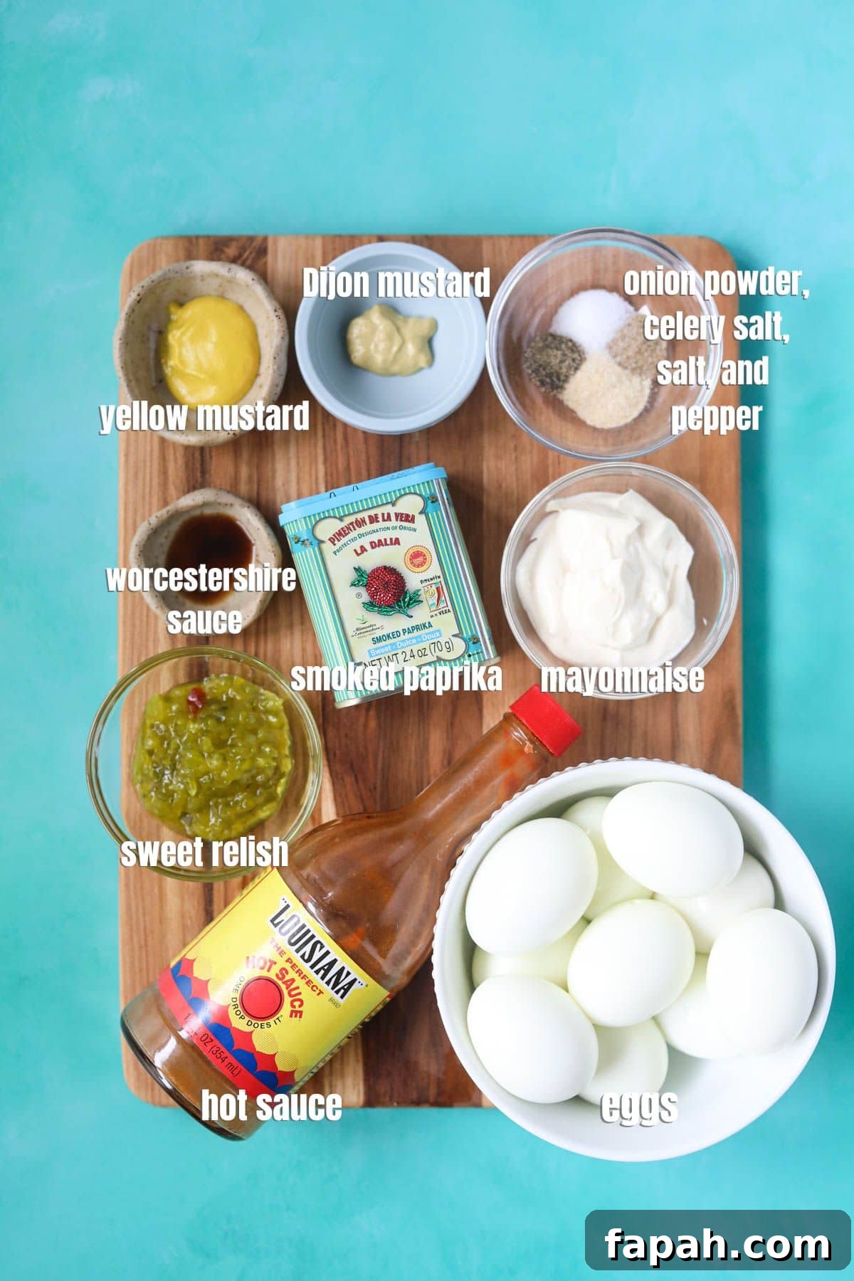 Ingredients for making southern deviled eggs arranged on a wooden cutting board.