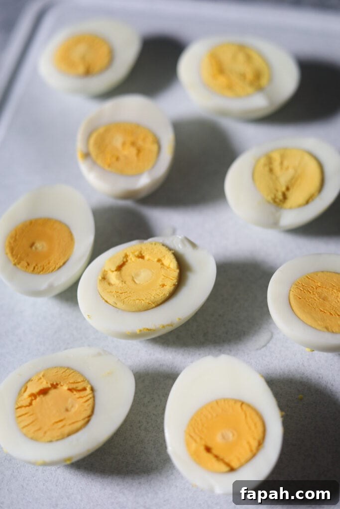 Hard boiled eggs sliced in half sitting on a white surface.