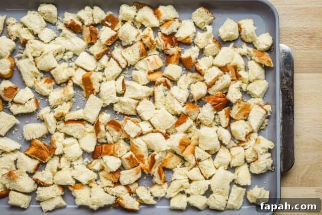 Savory Sausage and Brioche Stuffing Recipe 4 Brioche cubes on a baking sheet ready to dry in the oven to make sausage brioche stuffing.