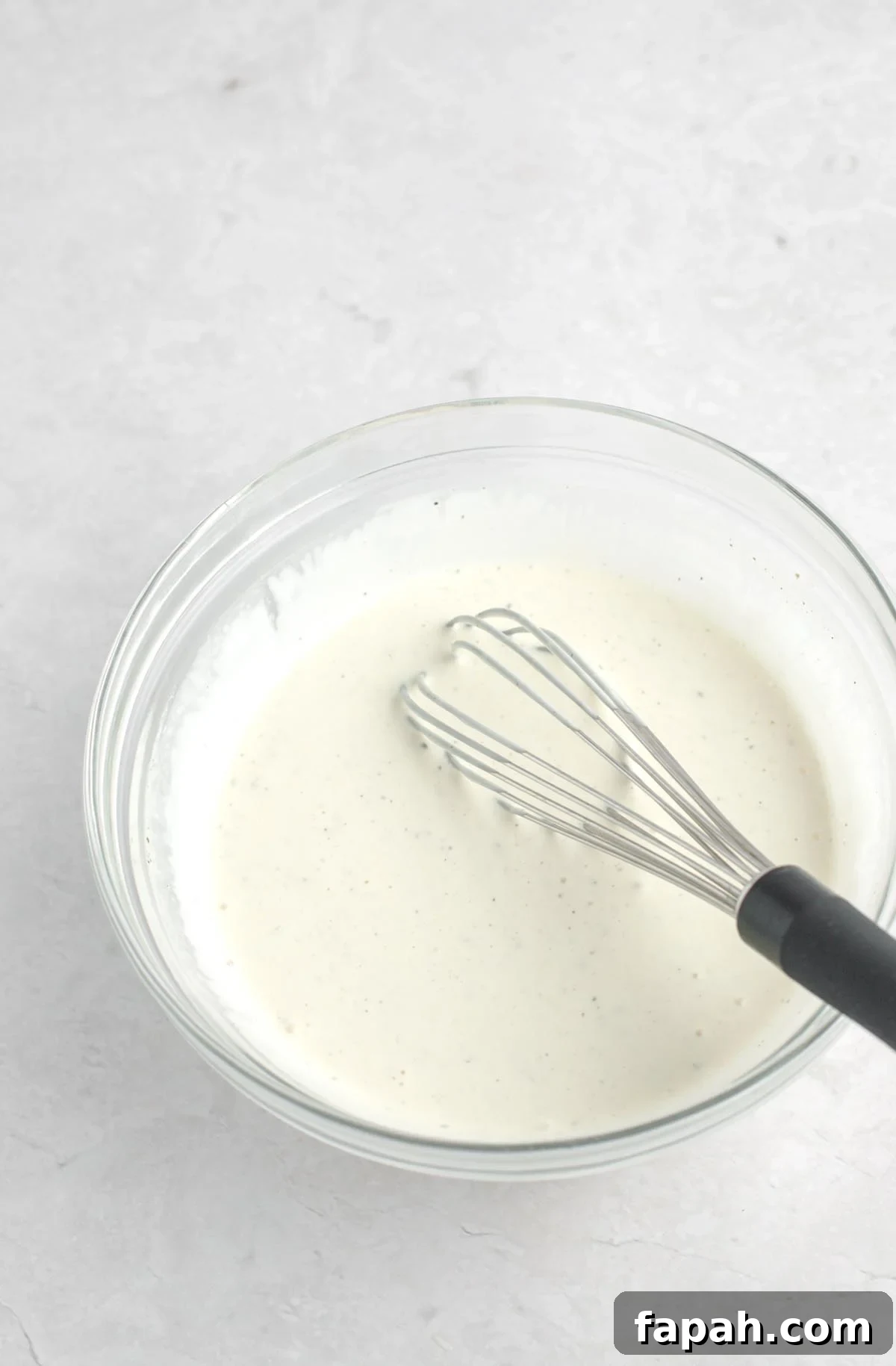 Broccoli salad dressing in a bowl with a whisk.