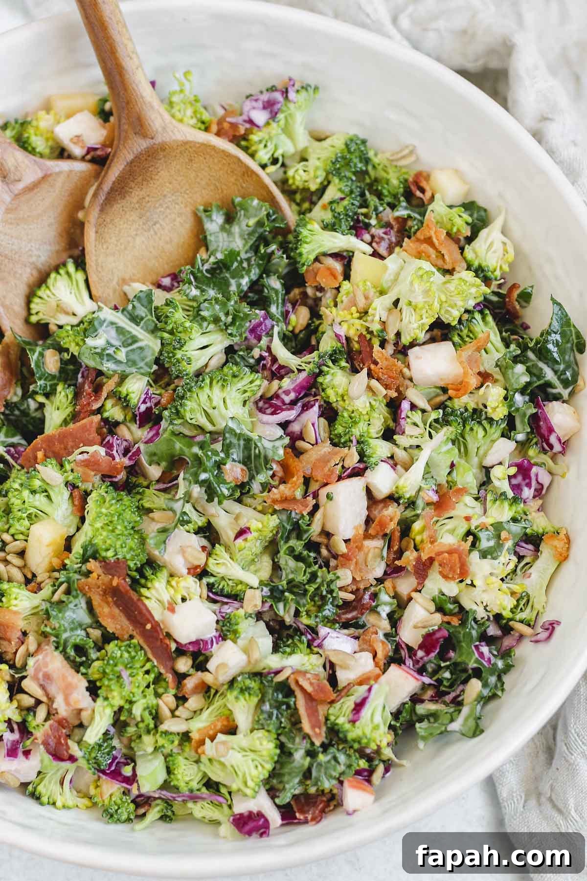 close up of broccoli salad with wooden salad utensils