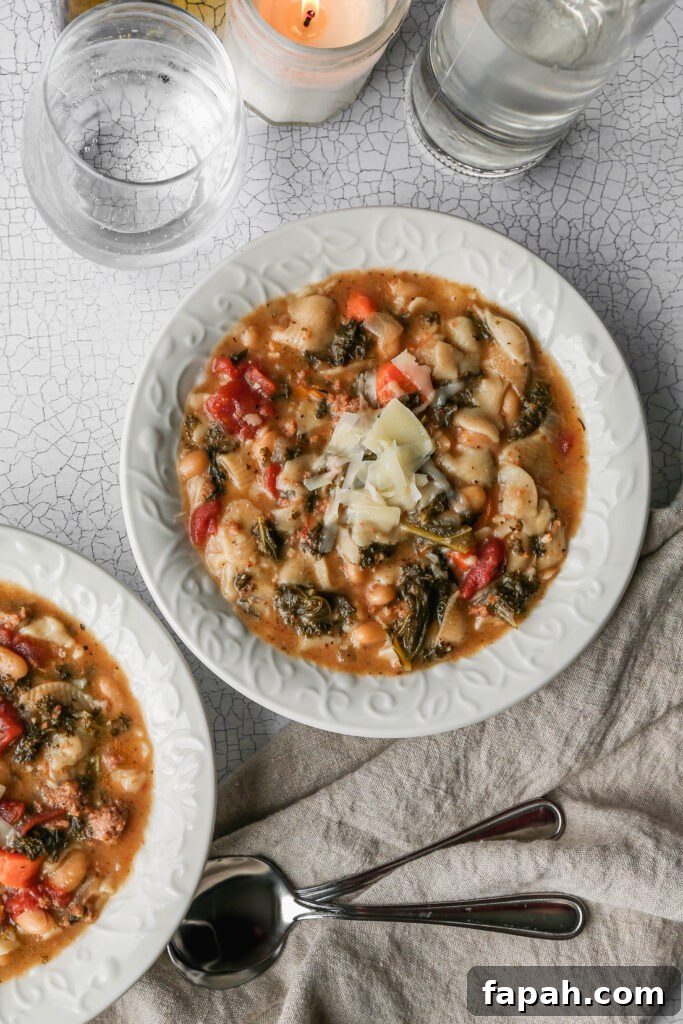 two white bowls of gluten free instant pot Italian style pasta and bean soup next to a glass of sparkling water and two soup spoons.