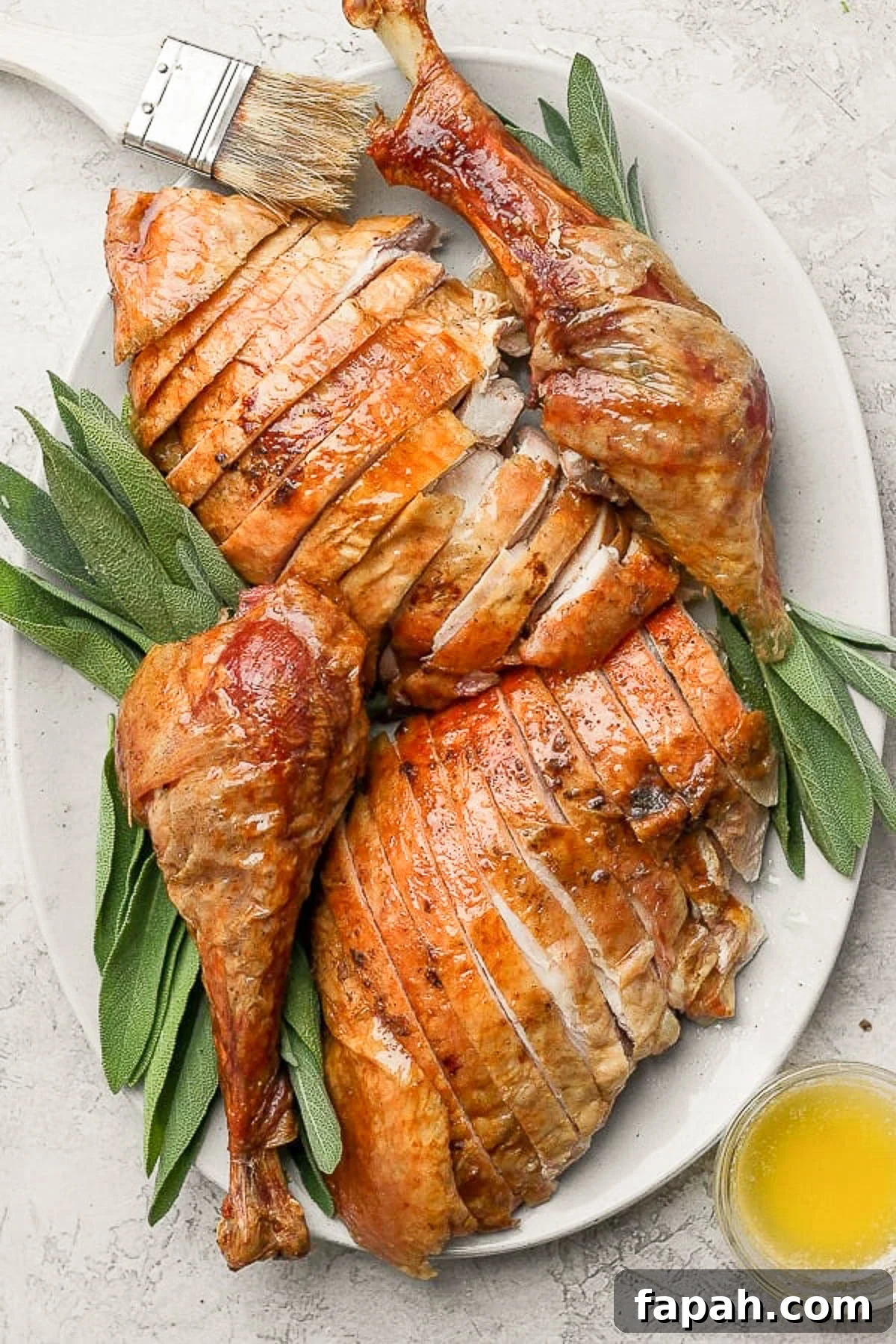 A whole smoked turkey cut up and on a platter with some fresh herbs.