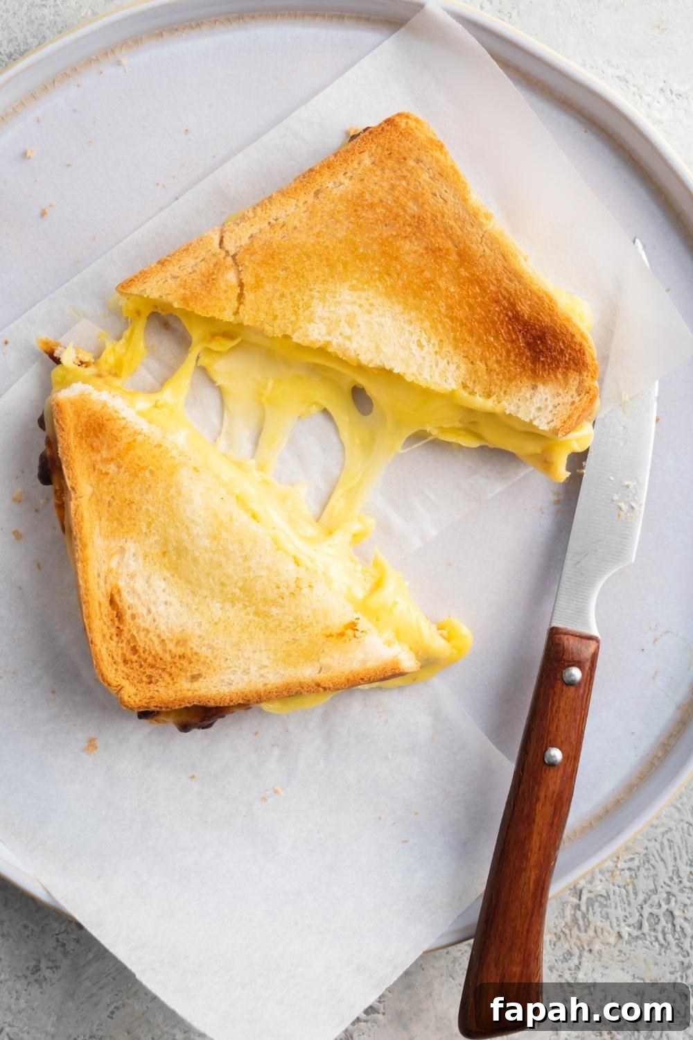 A piece of grilled cheese sliced in half on top of parchment paper on a plate.