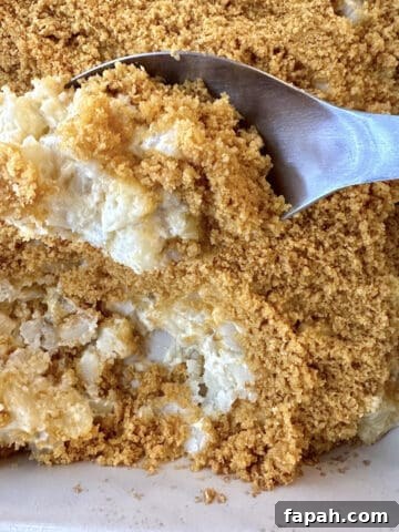 A spoon scooping up country potatoes from a baking dish.