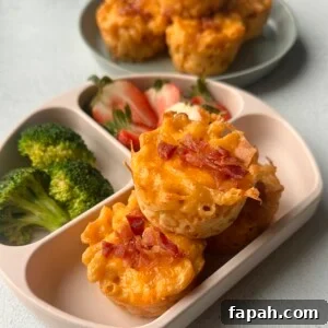 Mac and cheese muffins served with strawberries and broccoli.
