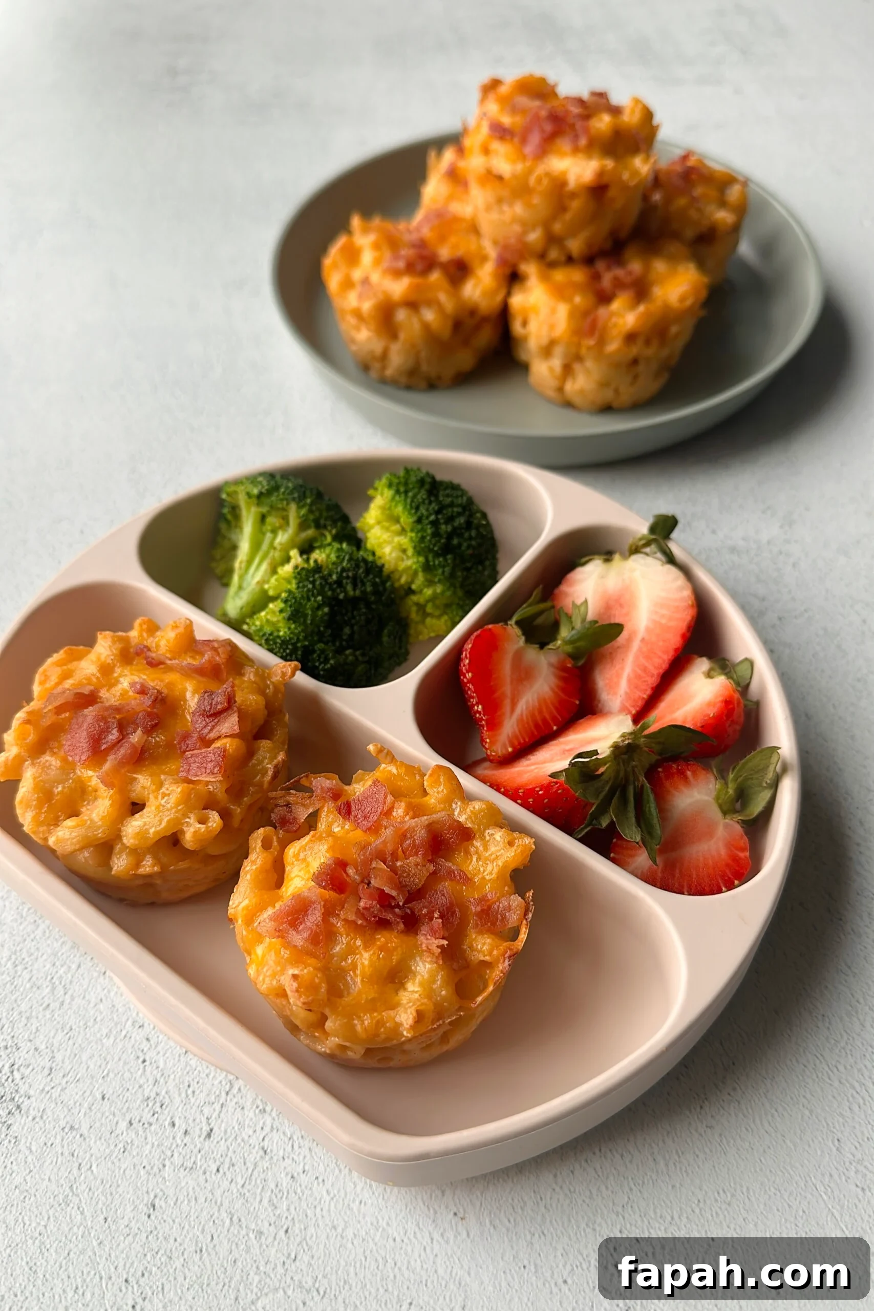 Mac and cheese muffins served with strawberries and broccoli.