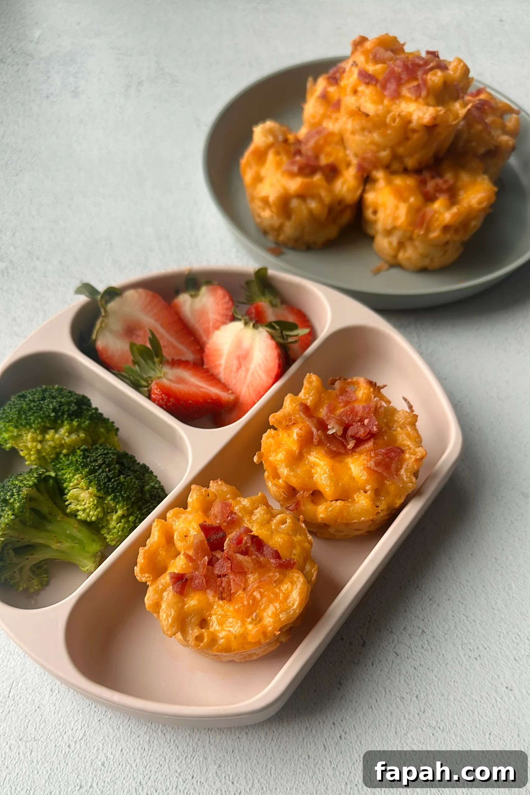 Mac and cheese muffins served with strawberries and broccoli.
