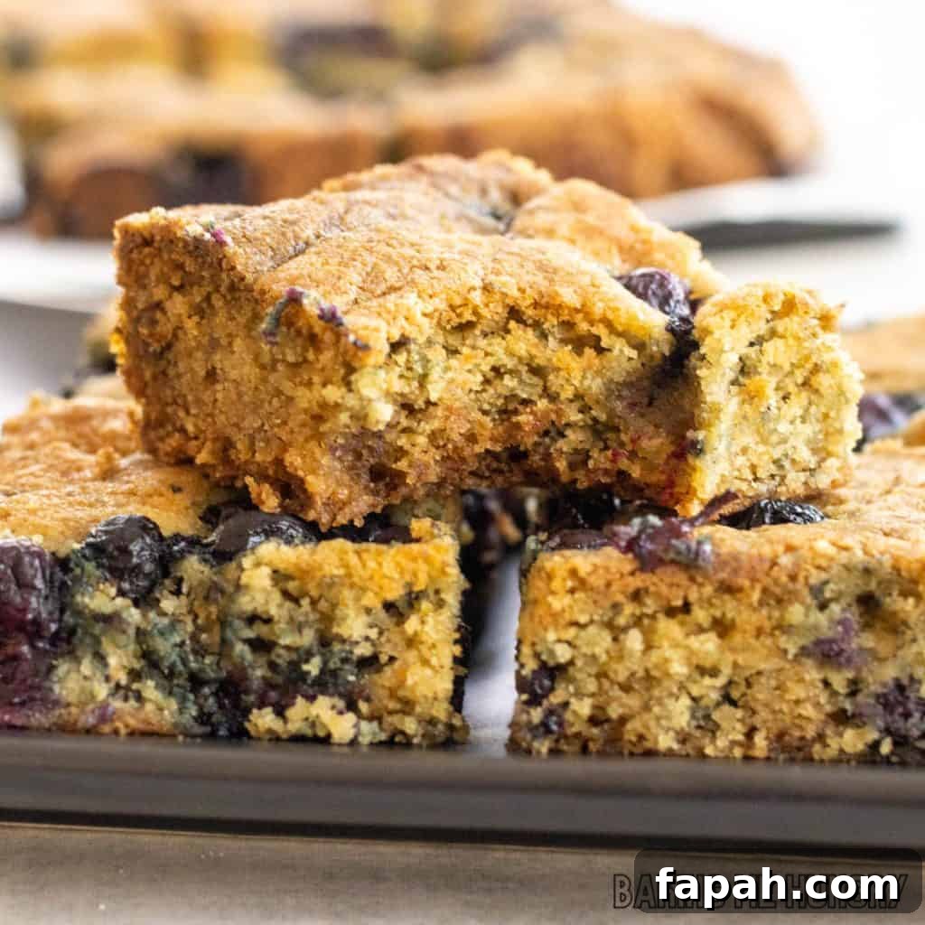 Chewy Blueberry Blondies with Lemon Glaze 3 blueberry blondies recipe on serving tray with top bar missing a bite