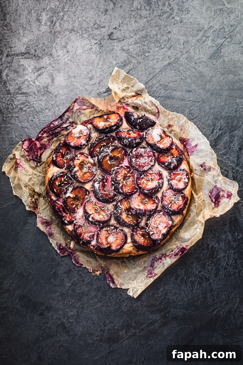 Plum, Walnut and Lavender Cake, overhead shot on a black background.