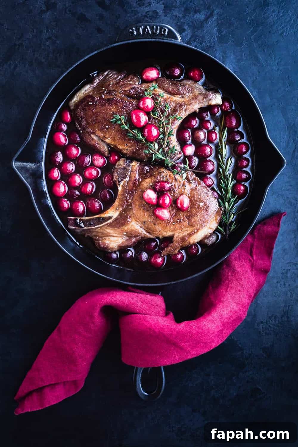 Searing pork chops in a skillet with cranberry glaze, overhead shot.