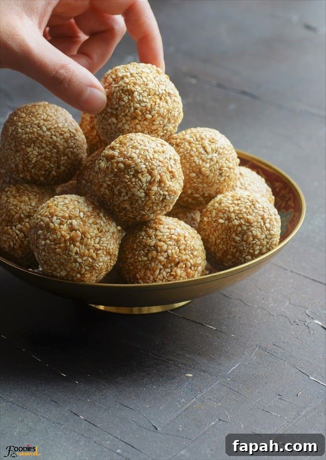Sesame Ladoo Recipe: Traditional Til Laddu for Festivals 2 Til Laddu stacked on a golden bowl