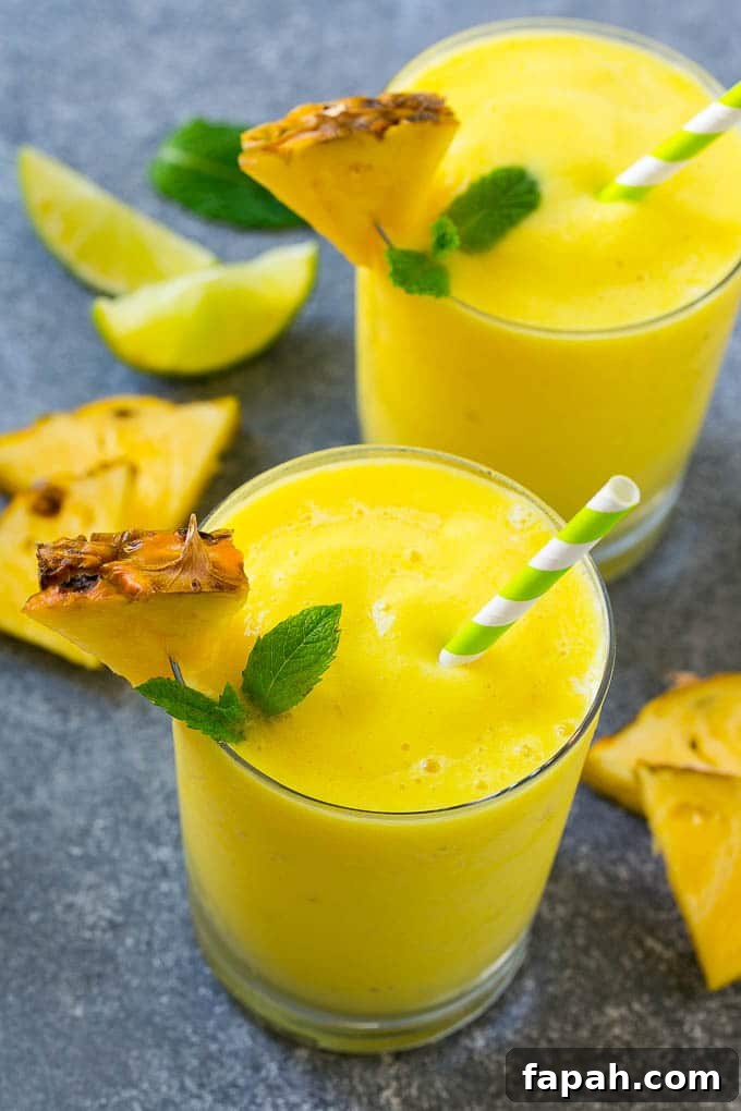 Glasses of blended pineapple smoothie with mint garnish.