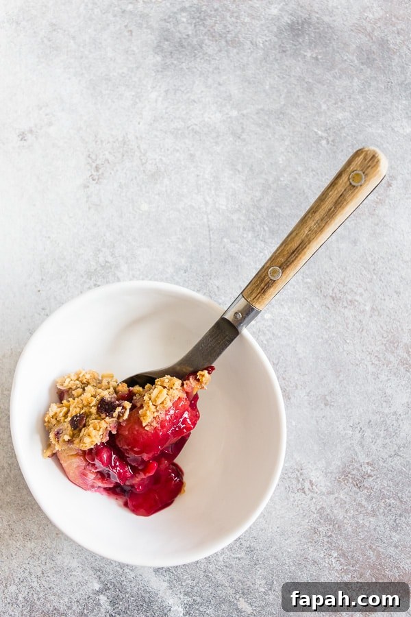 Cardamom Vanilla Plum Crisp with Almond Oat Streusel 4 Cardamom Vanilla Plum Crisp spooned into a small white bowl.