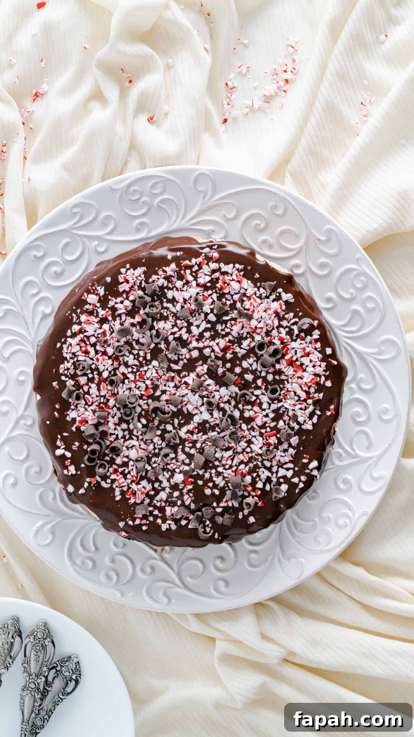 A 7 inch instant pot cheesecake topped with ganache, crushed peppermints, and chocolate curls.