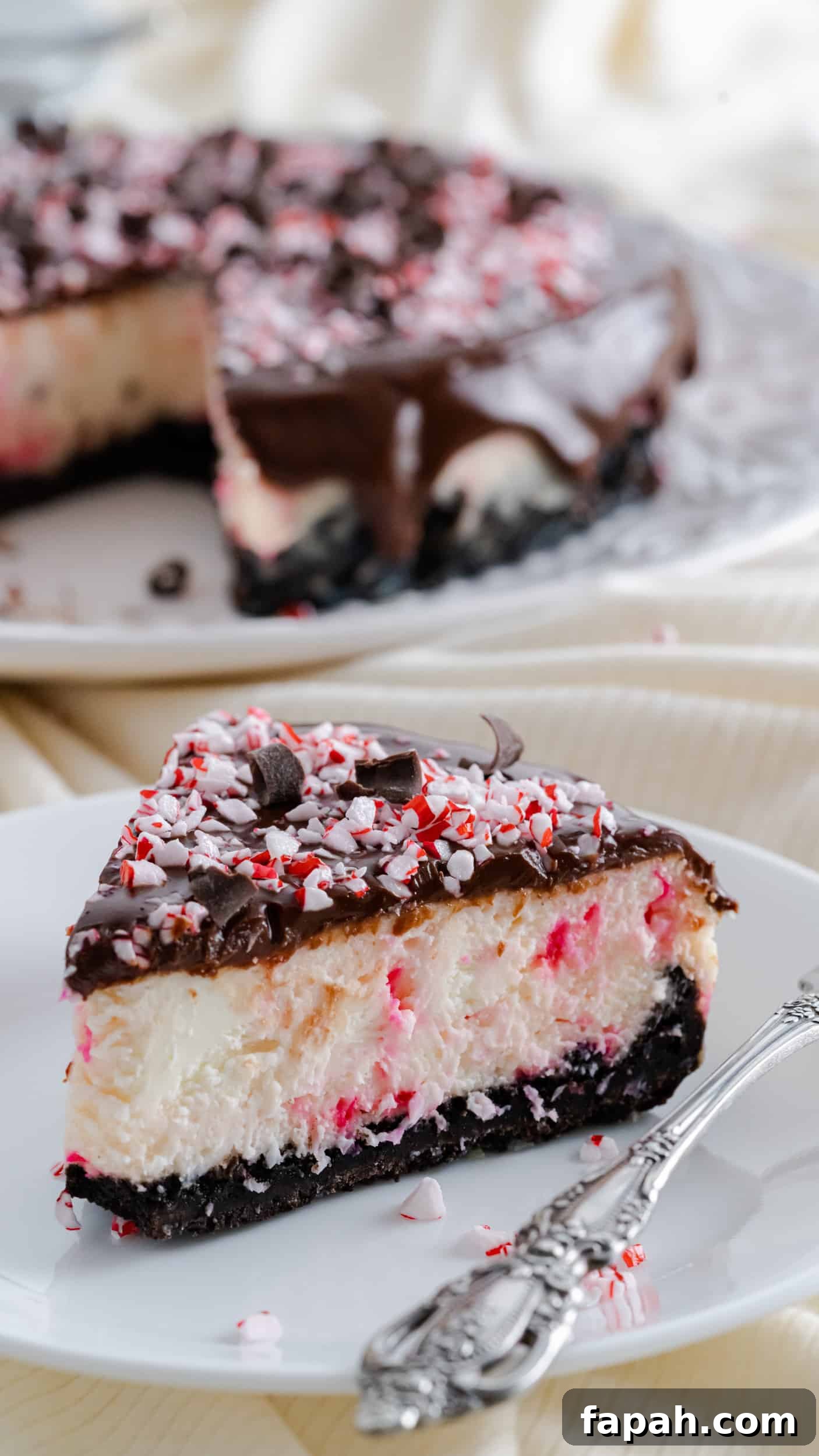 Slice of Instant Pot Peppermint Cheesecake on a white plate and decorative fork.