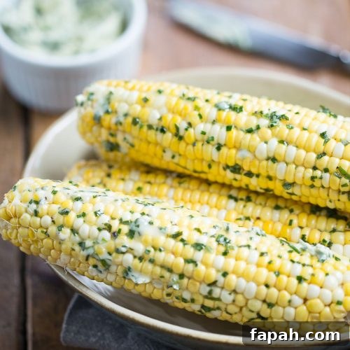 corn on the cob with herb butter sitting in a cream bowl