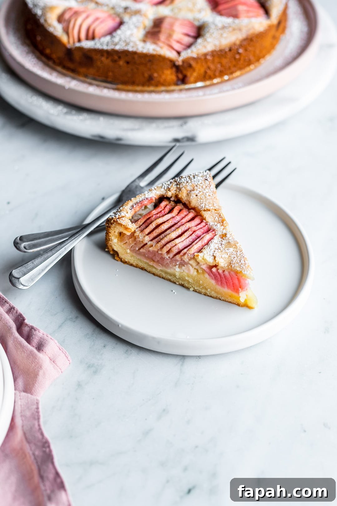 Almond Cake with Roasted Pink Apples 3 Slice of almond cake with pink apples on a white plate and marble background