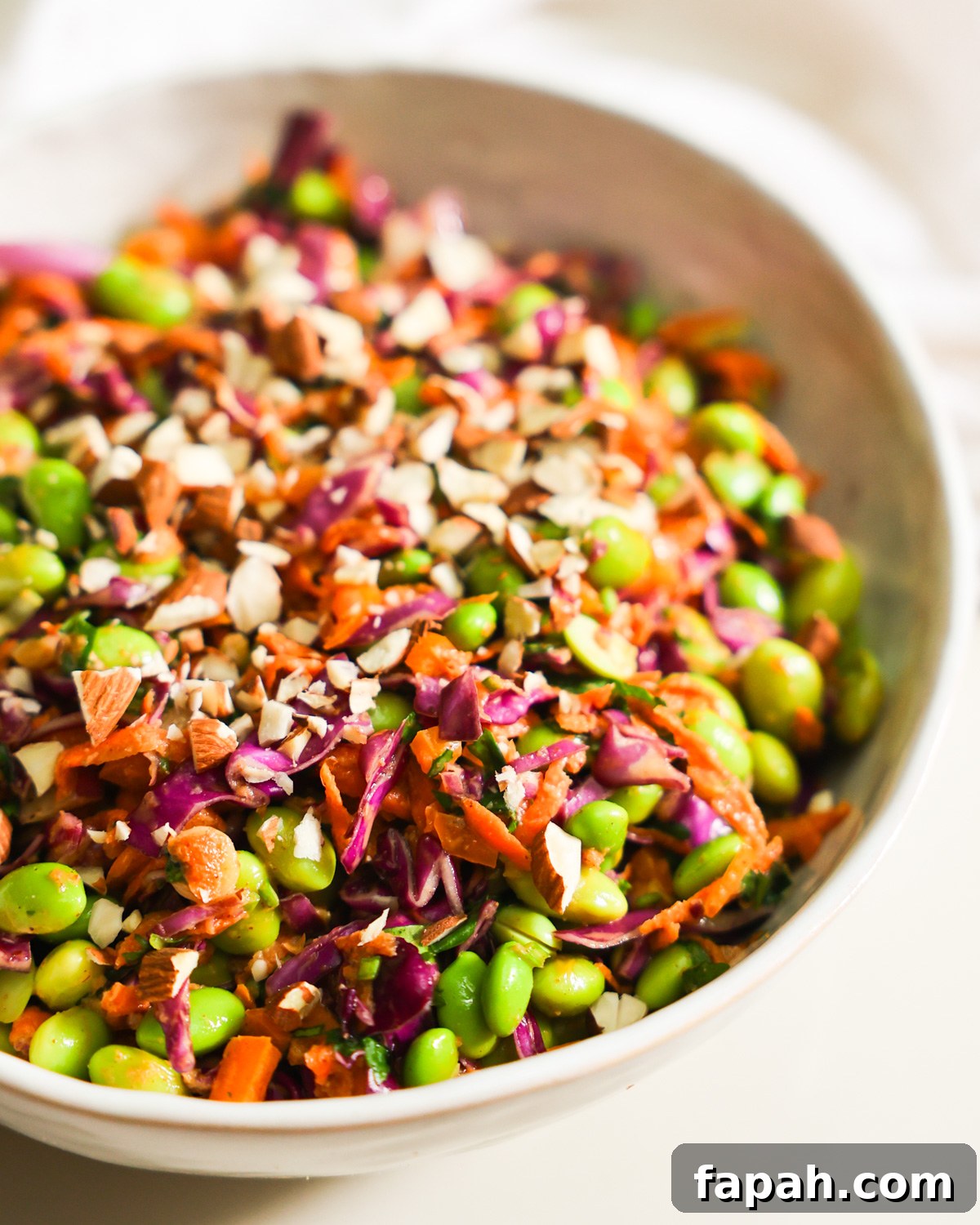 Crisp Edamame Salad with Lemon-Ginger Vinaigrette 9 A close-up side shot of a bowl of edamame salad garnished with chopped almonds.
