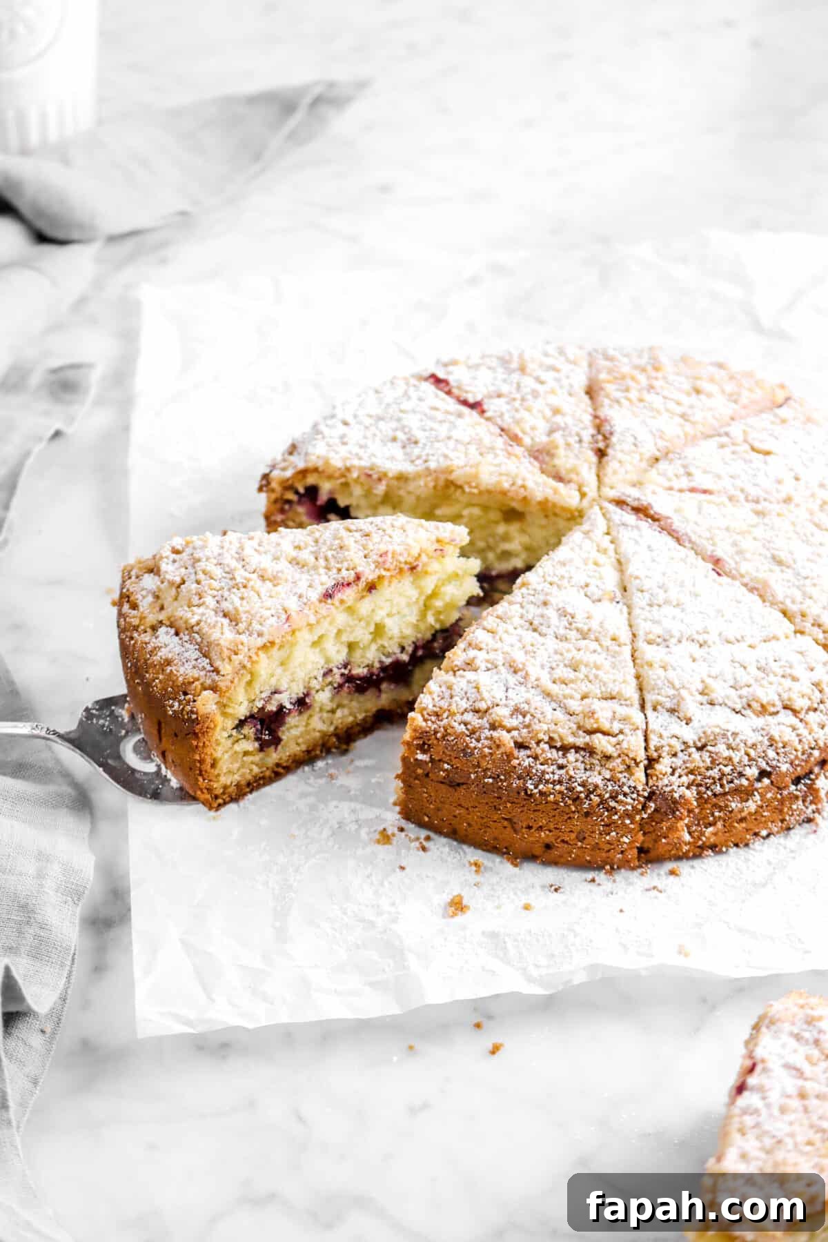 blueberry coffee cake on parchment paper with slice being pulled out
