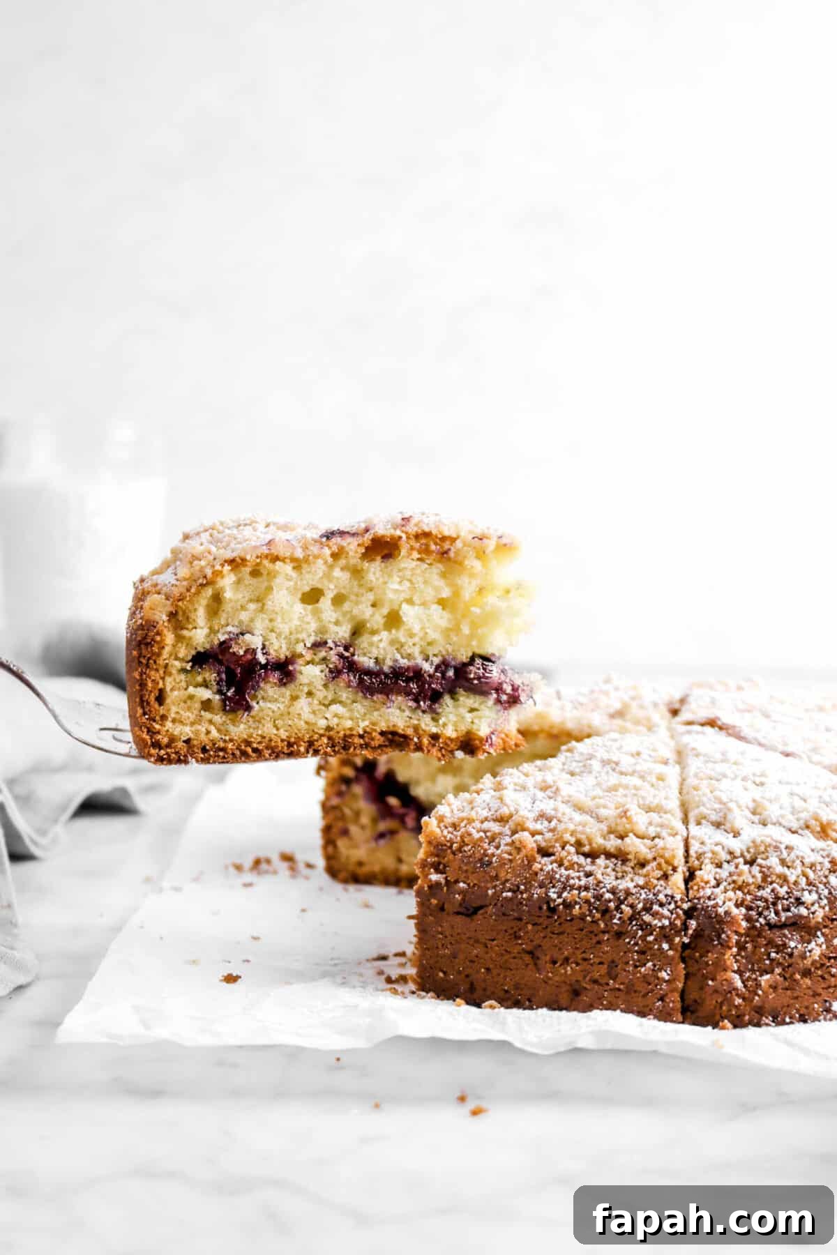 slice of blueberry coffee cake being held over cake