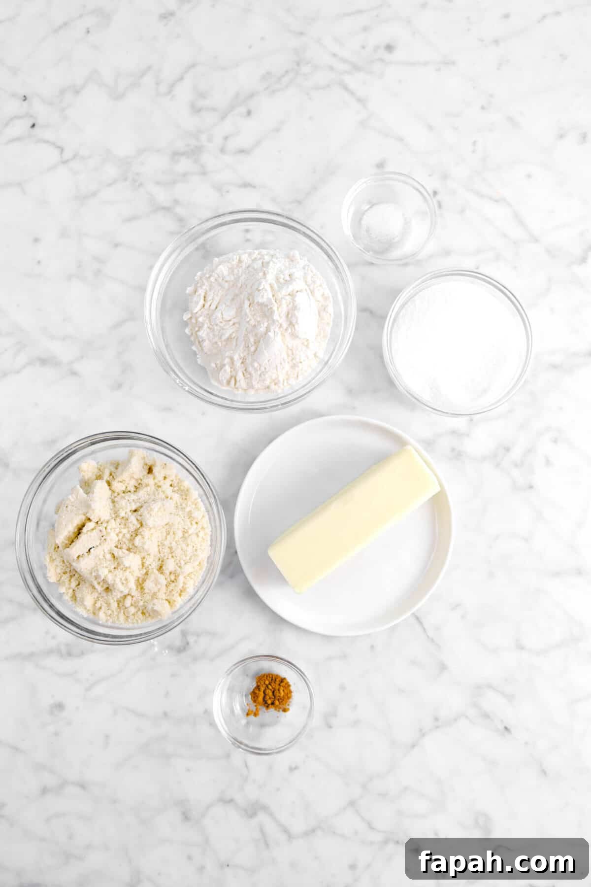 salt, sugar, flour, butter, almond flour, and cinnamon on marble counter