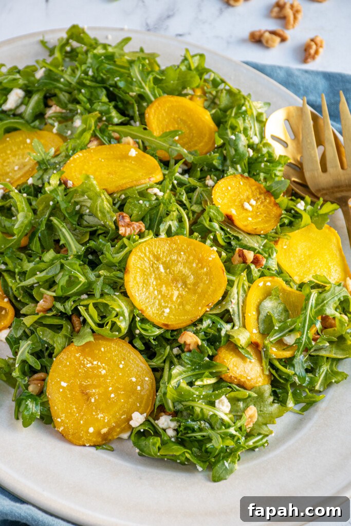Arugula & Roasted Golden Beet Salad with Citrus Vinaigrette 8 Close up of golden beets onto top of a bed of arugula with feta cheese and chopped walnuts.